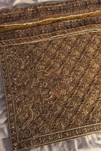 Close-up of a gold embroidered fabric with intricate patterns on a white background