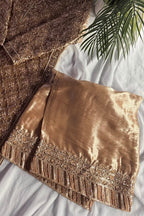 Gold textured fabric with intricate patterns on a white surface.